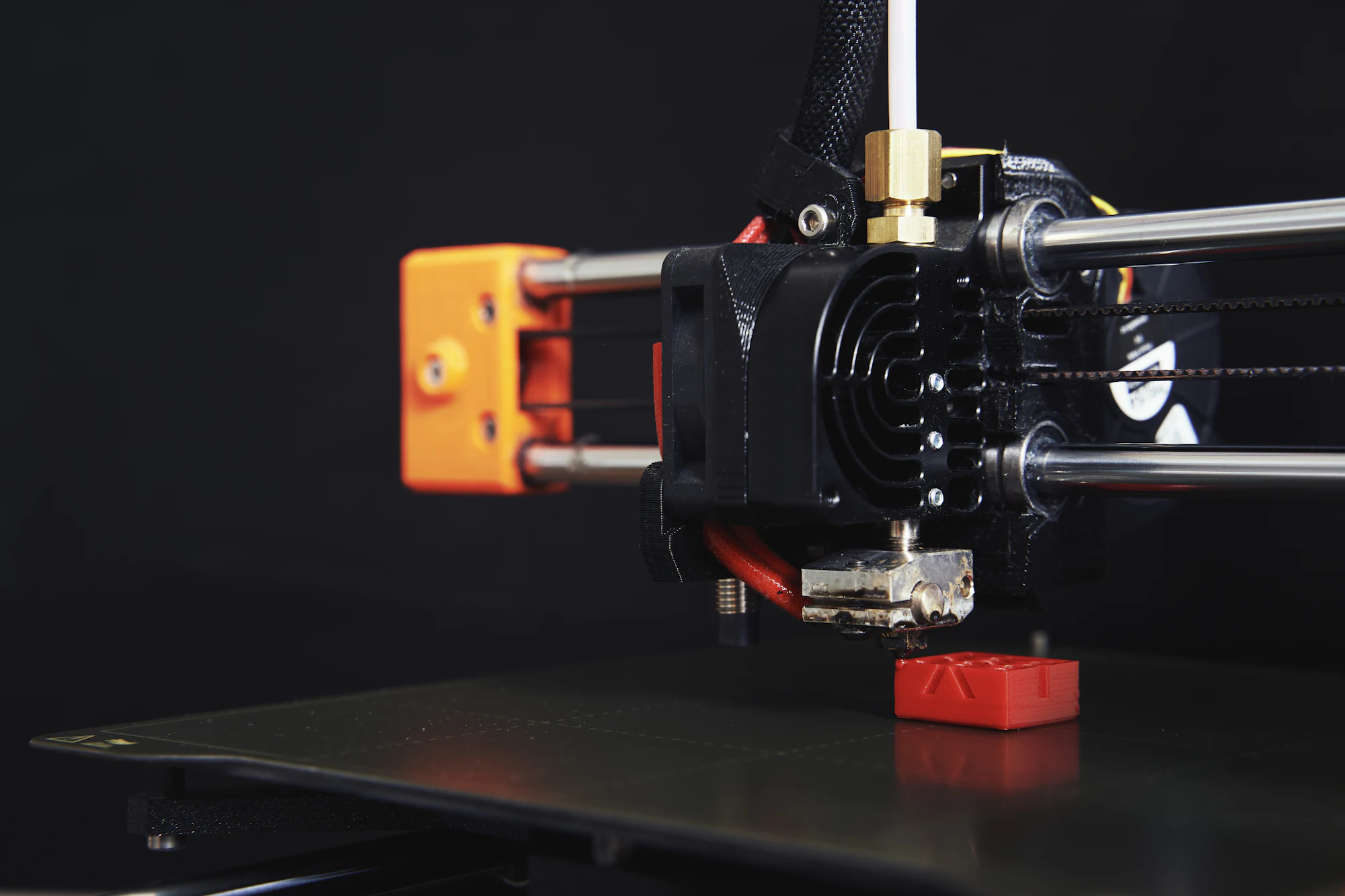 Extrusora de impressora 3D FDM em close, com filamento sendo depositado