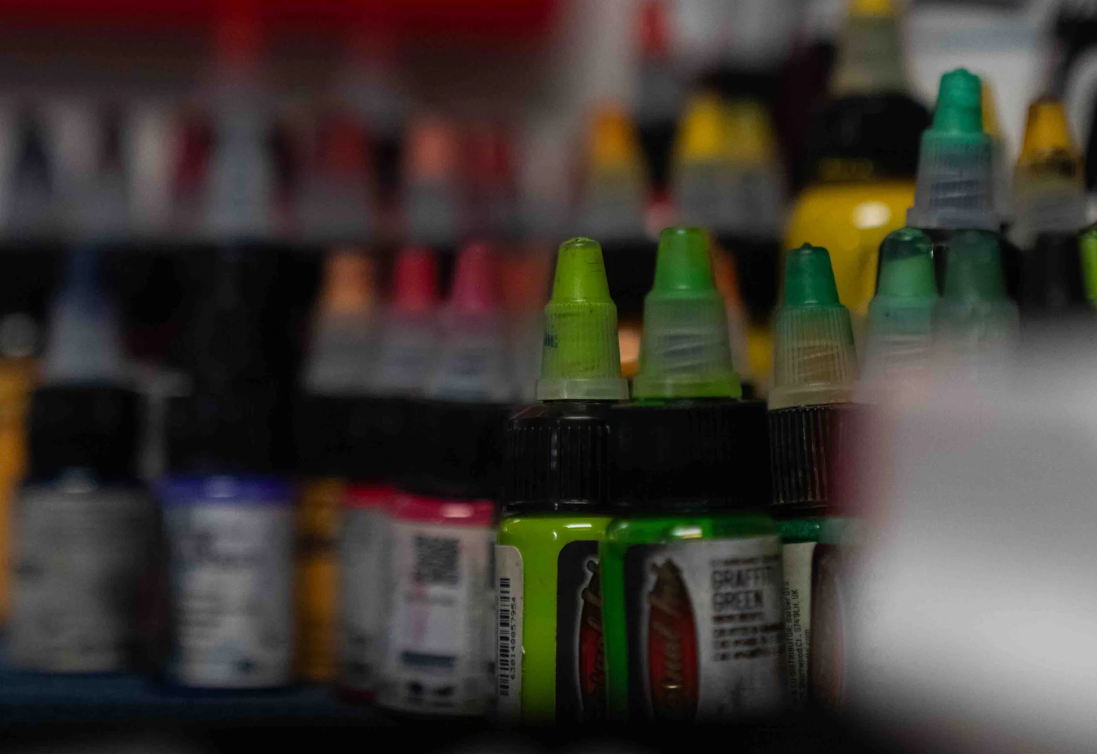 Potes de tinta acrílica organizados por cor na bancada de pintura